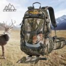 Framed leaf-camo saddle hunting backpack with integrated fold-down tree-stand seat displayed in a mountain meadow setting